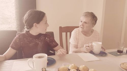 Woman sitting by coffee cup on table