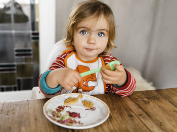 Cute girl having breakfast sitting at home