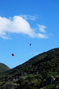 Low angle view of balloons flying against blue sky