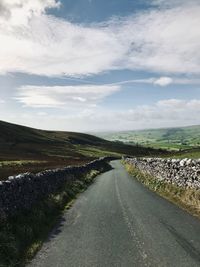 Road amidst field against sky