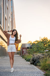 Full length of young woman standing against sky