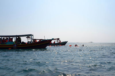 People on boat sailing in sea against clear sky