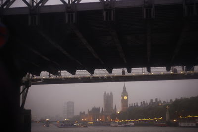 Illuminated bridge over river in city at night