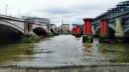 Bridge over river in city against sky