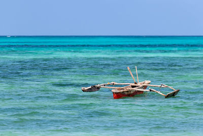 Boat sailing in sea against clear sky