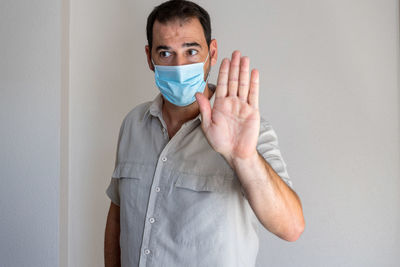 Man wearing flu mask gesturing while looking away at home