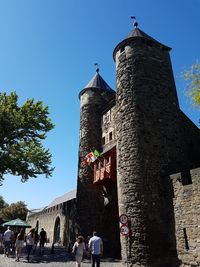 People at historic building against clear sky