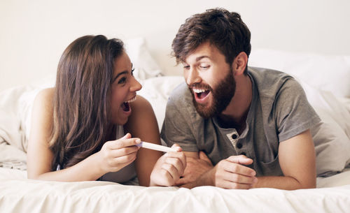 Happy couple lying on bed at home