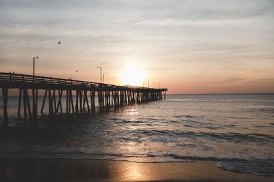 Pier over sea against sky during sunset
