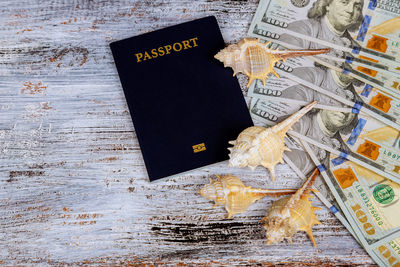 Close-up of passport book with shells and paper currencies on wooden table