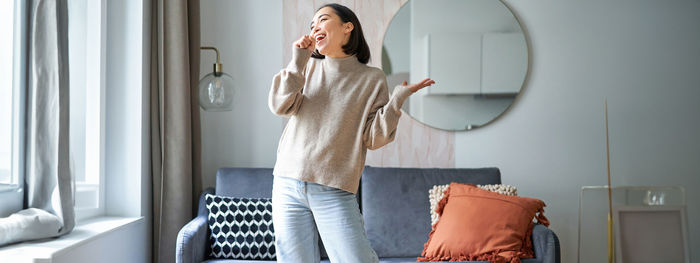 Young woman using mobile phone while sitting on sofa at home