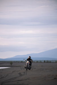 Rear view of woman walking on beach against sky