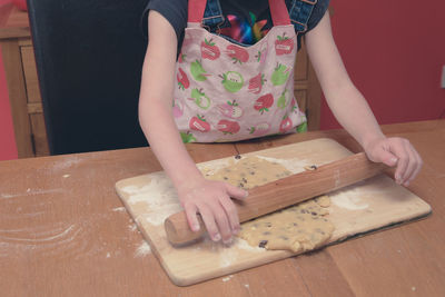 Midsection of girl preparing rolling dough at home