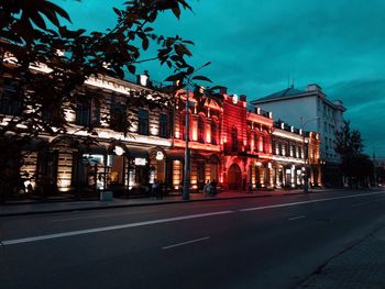 City street by buildings against sky at dusk