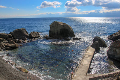 Rocks on sea shore against sky