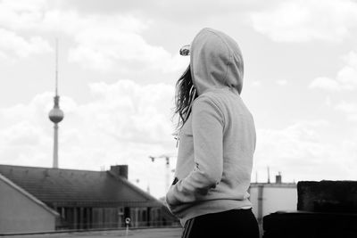 Rear view of woman standing against sky in city