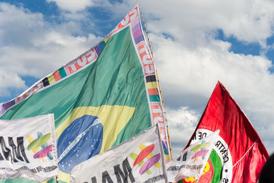 Low angle view of flags against cloudy sky