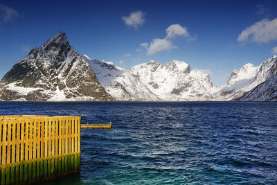 Scenic view of sea by snowcapped mountains against sky