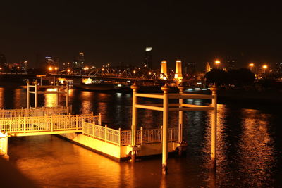 Illuminated bridge over river in city at night