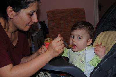 Mother feeding son at home