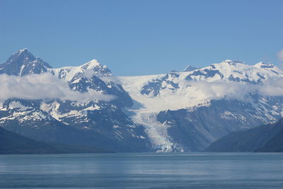 Scenic view of lake and snowcapped mountains against clear blue sky