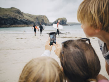 Woman taking selfie with kids from mobile phone at beach