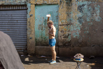 Full length of shirtless boy standing against wall