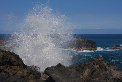 Waves splashing on rock formation against sea