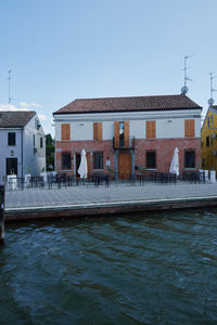 Buildings by river against clear sky