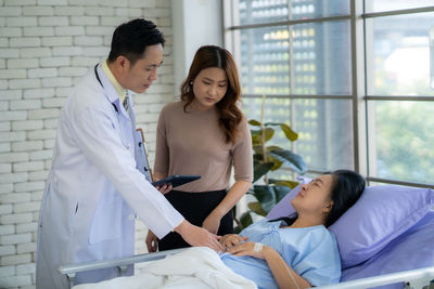 Portrait of young woman using digital tablet while standing in hospital