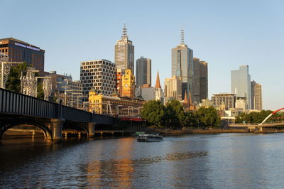 Bridge over river in city against clear sky