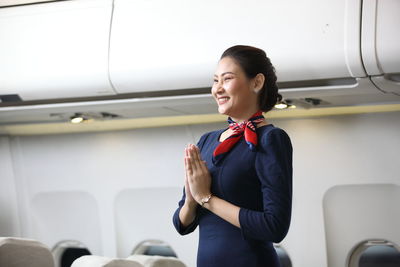 Young woman standing on seat in airplane