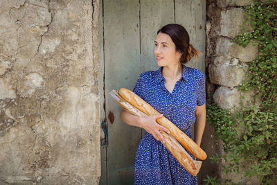 Young woman standing with french baguettes in the countryside