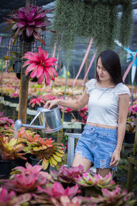 Woman standing by pink flowering plants