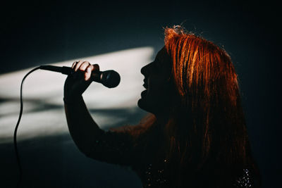 Silhouette, profile of female singer woman holding microphone. excited female singer with modern