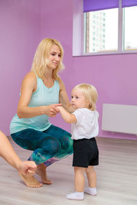 Mom and baby are doing exercises with an instructor in the gym.