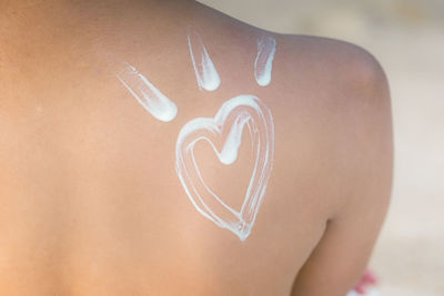 Midsection of woman back with heart shaped moisturizer