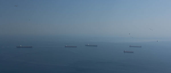 Boats sailing in sea against clear sky