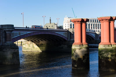 Bridge over river against sky in city