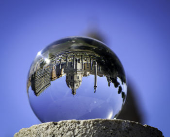 Close-up of crystal ball against blue sky