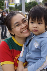 Portrait of smiling mother embracing cute son