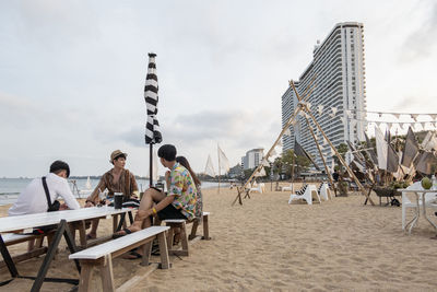 People sitting on table at beach against sky