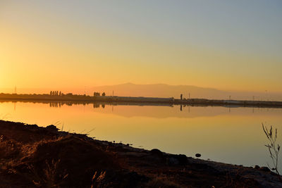 Scenic view of lake against clear orange sky