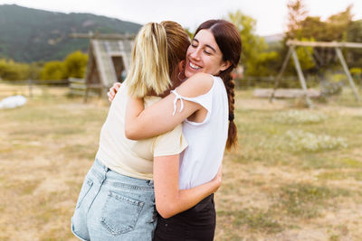 Side view of friends embracing outdoors