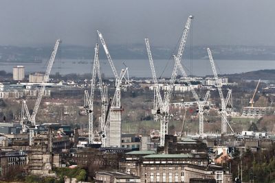 High angle view of cranes in city against sky