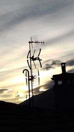 Low angle view of silhouette communications tower against sky during sunset