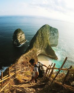 High angle view of young man moving down on rock formations by sea