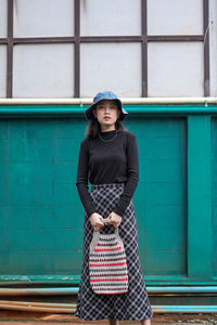 Portrait of woman standing against building