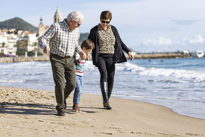 Happy grandparents with grandson walking at beach