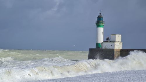 Lighthouse by sea against sky